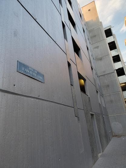 Street sign "Rue de l'ancienne gare" on a car park with about 5 stories.